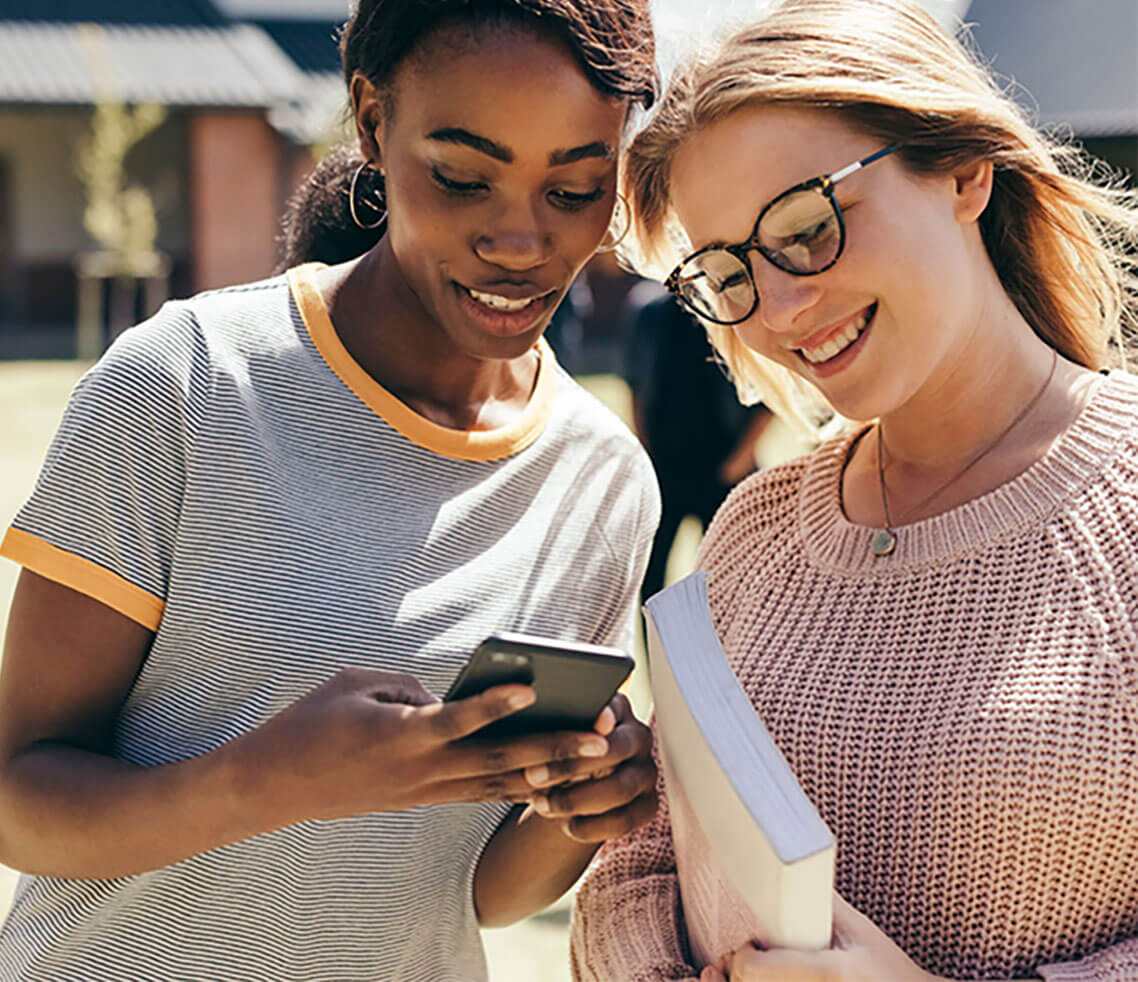 two women smiling at a cell phone